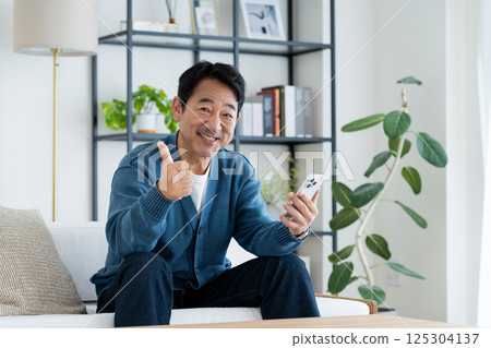 Middle-aged man using a smartphone in the living room 125304137
