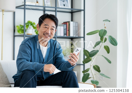 Middle-aged man using a smartphone in the living room 125304138