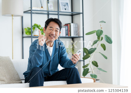 Middle-aged man using a smartphone in the living room Middle-aged man using a smartphone in the living room 125304139