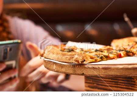 Close-up of pizza slices on a wooden stand in a cafe. Close-up of pizza slices on a wooden stand in a cafe. 125304522