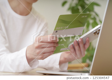 一位女士使用存摺和智慧型手機兌換貨幣 一位女士使用存摺和智慧型手機兌換貨幣 125304547