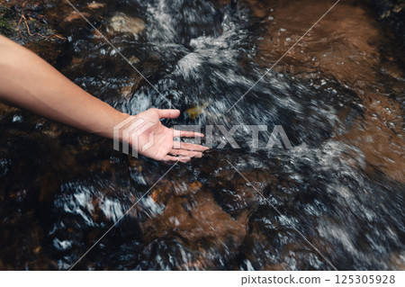 Hands touching the clean stream from the mountain, sustainable water and environment Hands touching the clean stream from the mountain, sustainable water and environment 125305928