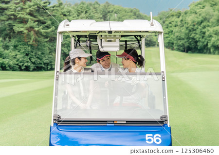 A golfer woman riding a golf cart on a golf course (golf girl) 125306460