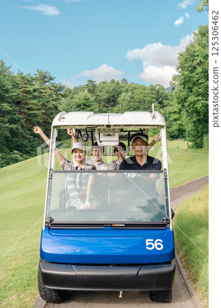 Golfer man and woman riding a golf cart on a golf course 125306462