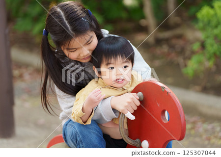 Siblings playing on spring play equipment in the park 125307044
