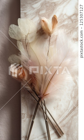 Elegant arrangement of soft feathers and translucent leaves on marble surface 125307127