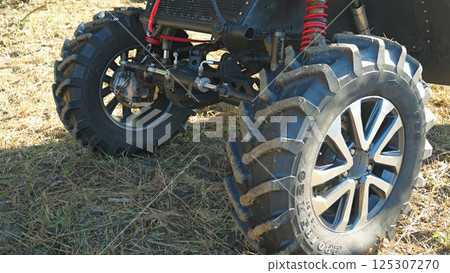 Close-up of a powerful off-road vehicle's front suspension and large, knobby tires. The vehicle is designed for extreme terrain Close-up of a powerful off-road vehicle's front suspension and large, knobby tires. The vehicle is designed for extreme terrain 125307270
