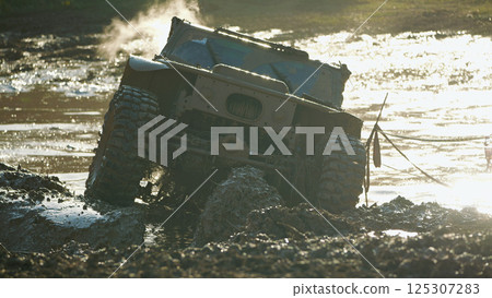 The off-road vehicle is stuck in a muddy ditch. Steam is rising from the engine. Dirty powerful SUV in a muddy puddle. Epic moment of extreme competition 125307283