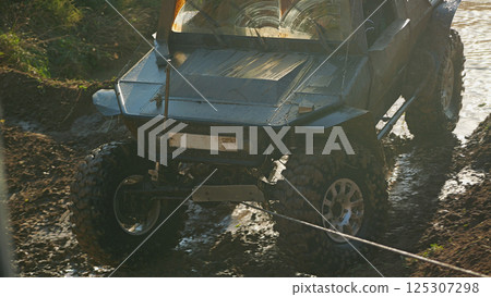 Off-road vehicle prepared for serious off-roading, with the help of a winch overcomes difficult terrain. The vehicle has large wheels with aggressive tread Off-road vehicle prepared for serious off-roading, with the help of a winch overcomes difficult terrain. The vehicle has large wheels with aggressive tread 125307298