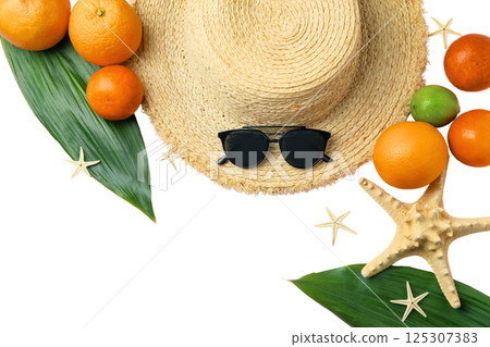 A straw hat surrounded by vibrant fruits on green leaves, isolated on white background 125307383