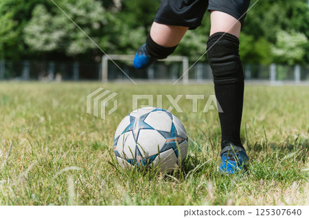Close-up of young football player kicking soccer ball. Close-up of young football player kicking soccer ball. 125307640