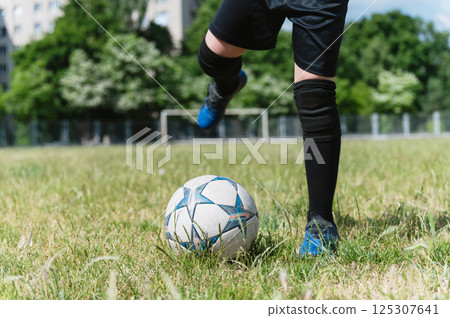 Close-up of young football player kicking soccer ball. 125307641