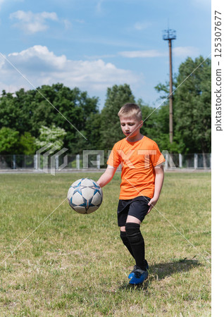 Boy kicking soccer ball on sunny grassy field. Boy kicking soccer ball on sunny grassy field. 125307677