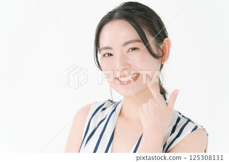 指著她的牙齒的年輕女子 指著她的牙齒的年輕女子 125308131