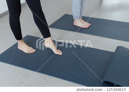 Slim female legs on a yoga mat. Healthy lifestyle and training of the body and spirit. Indoors close-up 125308615