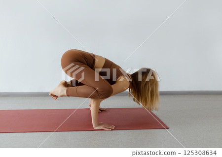 An attractive girl sits on a yoga mat. Slim body and health care.Crane Pose ,Bakasana 125308634