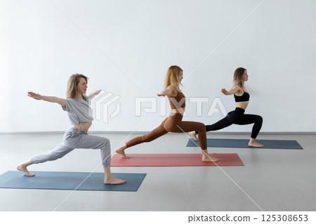Young girls in a warrior pose at a group yoga class. Healthy lifestyle and female beauty 125308653