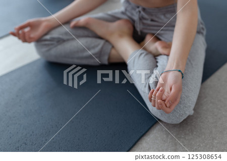 Close-up Athletic girl sitting in lotus position on yoga mat indoors .Yoga, fitness and healthy lifestyle 125308654