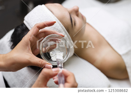 Close-up shot of a woman getting facial treatment with clay mask. Cosmetology and spa 125308682