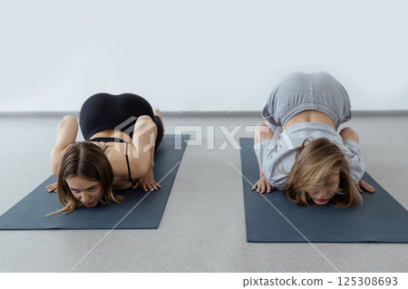 young flexible girl doing yoga and gymnastics indoor gymnastics, flexibility and stretching assana lying backbend young flexible girl doing yoga and gymnastics indoor gymnastics, flexibility and stretching assana lying backbend 125308693