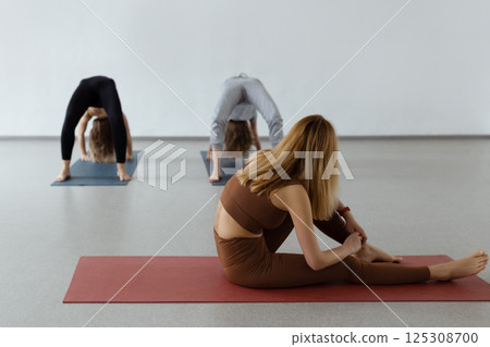 An attractive girl sits on a yoga mat. Slim body and health care. Urdhva Dhanurasana , Inverted Bow Pose or Bridge Pose 125308700