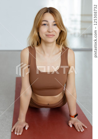 An attractive girl sits on a yoga mat. Slim body and health care.UP DOG , URDHVA MUKHA SVANASANA 125308732