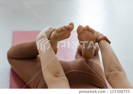 yoga asana activity deflection on the stomach close-up of the hands took hold of the legs. Body Stretching Fitness and Pilates yoga asana activity deflection on the stomach close-up of the hands took hold of the legs. Body Stretching Fitness and Pilates 125308755