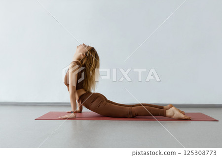 An attractive girl sits on a yoga mat. Slim body and health care.UP DOG , URDHVA MUKHA SVANASANA 125308773