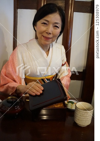 A woman in a kimono pouring tea and eating eel rice A woman in a kimono pouring tea and eating eel rice 125308979