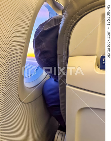 Person resting on airplane seat with view through window at sunset. High quality photo Person resting on airplane seat with view through window at sunset. High quality photo 125309645