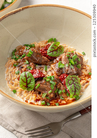 Portion of pasta orzo with meat and basil Portion of pasta orzo with meat and basil 125309940