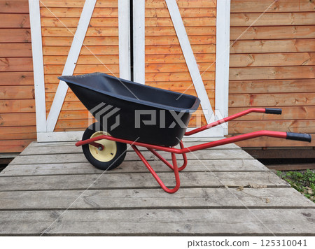 black wheelbarrow parked in the barn doors 125310041
