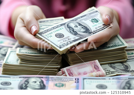 手裡拿著一疊鈔票和粉紅色指甲象徵女性的財務實力 手裡拿著一疊鈔票和粉紅色指甲象徵女性的財務實力 125310945