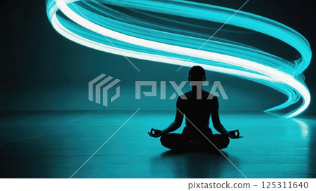 A person sits in a meditative pose on a smooth surface, surrounded by an ambiance of calm. The background features swirling light trails in vibrant shades that enhance the peacefulness of the moment 125311640