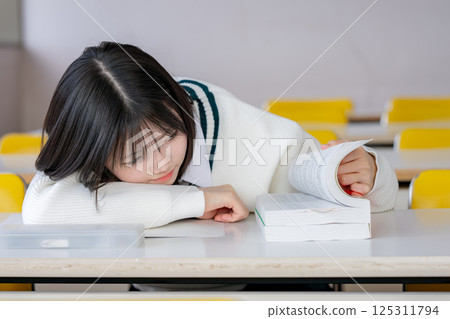 一名女學生趴著打開課本 125311794