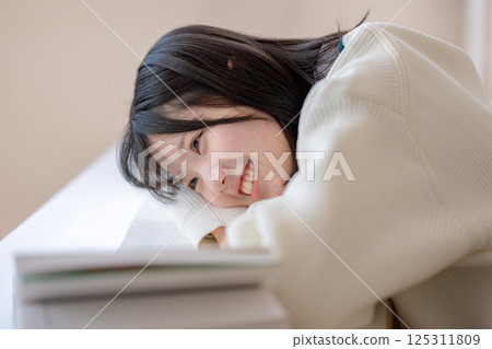 一名微笑的學生躺在桌上 一名微笑的學生躺在桌上 125311809