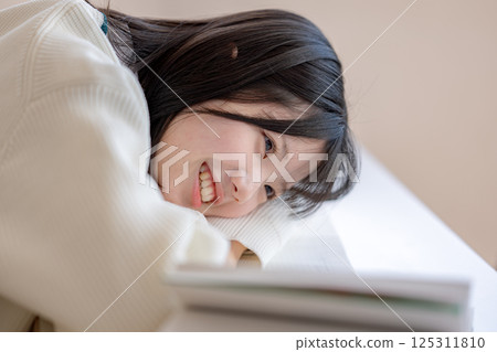 一名微笑的學生躺在桌上 125311810