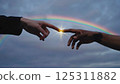 In this touching moment, two diverse hands extend toward each other against a backdrop of a vivid rainbow. The scene captures a sense of unity and connection, with a bright light glowing at the point 125311882