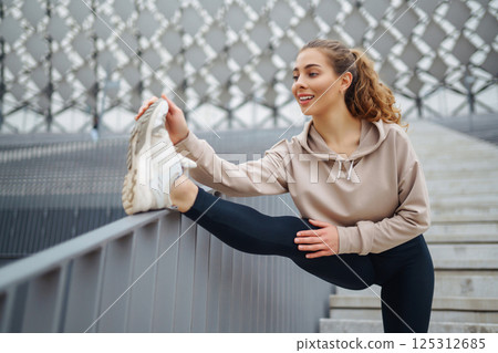 Young woman practices yoga with in modern outdoor setting during afternoon. People, fitness concept Young woman practices yoga with in modern outdoor setting during afternoon. People, fitness concept 125312685