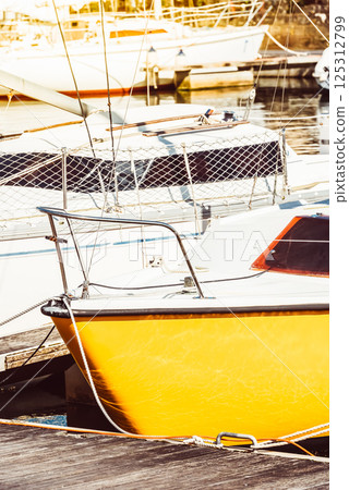 Yellow sailboat in sunny marina setting with several other boats, perfect for summer background Yellow sailboat in sunny marina setting with several other boats, perfect for summer background 125312799