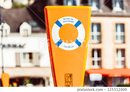 Orange life buoy station with signage on urban street, background 125312800