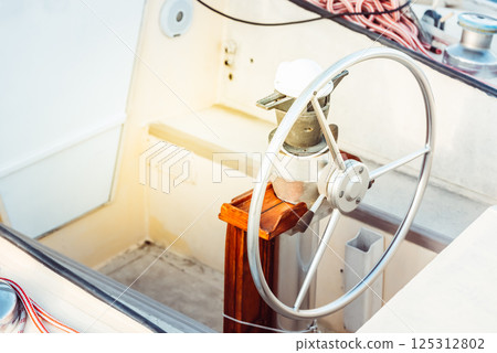 Sailboat steering wheel and deck with ropes in sunlight, suitable as a background 125312802