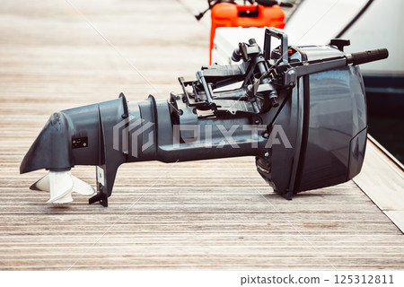 Boat motor on wooden dock near water, suitable for marine backgrounds 125312811