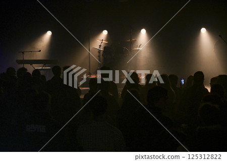 Energetic concert atmosphere with excited audience waiting for performance in a dimly lit venue Energetic concert atmosphere with excited audience waiting for performance in a dimly lit venue 125312822
