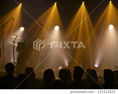 Musicians prepare for a lively concert with colorful lighting and engaged audience silhouetted Musicians prepare for a lively concert with colorful lighting and engaged audience silhouetted 125312824