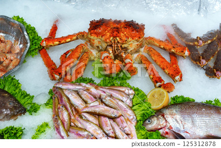 Fresh seafood display featuring crab and various fish at a market in the afternoon Fresh seafood display featuring crab and various fish at a market in the afternoon 125312878