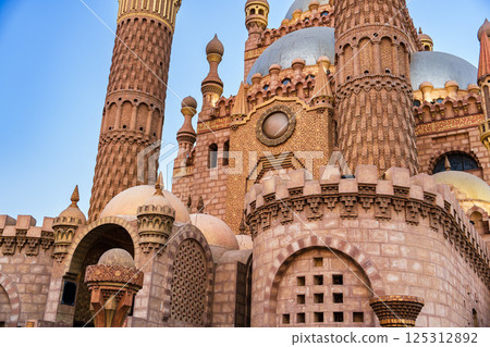Stunning architecture of a traditional castle with elaborate towers and detailed walls in a sunny outdoor setting Stunning architecture of a traditional castle with elaborate towers and detailed walls in a sunny outdoor setting 125312892