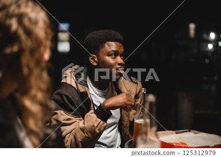 Friends enjoying late-night conversation at a cozy cafe in an urban setting 125312979