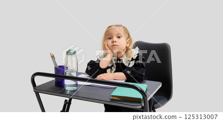 Bored girl resting head on hand while sitting at school desk with pencils, books and water bottle. Concept of school fatigue Bored girl resting head on hand while sitting at school desk with pencils, books and water bottle. Concept of school fatigue 125313007