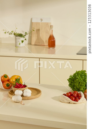Garlic bulbs placed randomly on a round wooden tray, next to a bowl of red peppers. Bright yellow bell peppers, small round cherry tomatoes and eye-catching green celery. Kitchen background. Garlic bulbs placed randomly on a round wooden tray, next to a bowl of red peppers. Bright yellow bell peppers, small round cherry tomatoes and eye-catching green celery. Kitchen background. 125313036